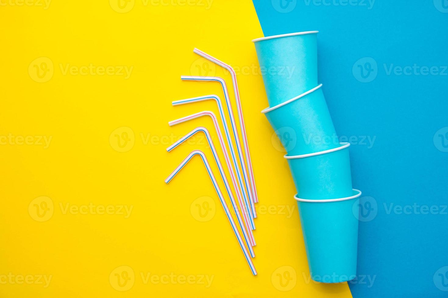bicchieri di carta blu con cannucce di plastica colorate su sfondo giallo e blu foto