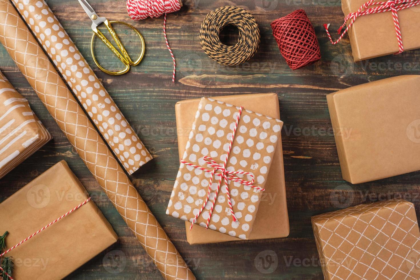 confezione regalo natalizia fatta a mano con decorazioni in carta marrone con abete di pino su tavola di legno foto