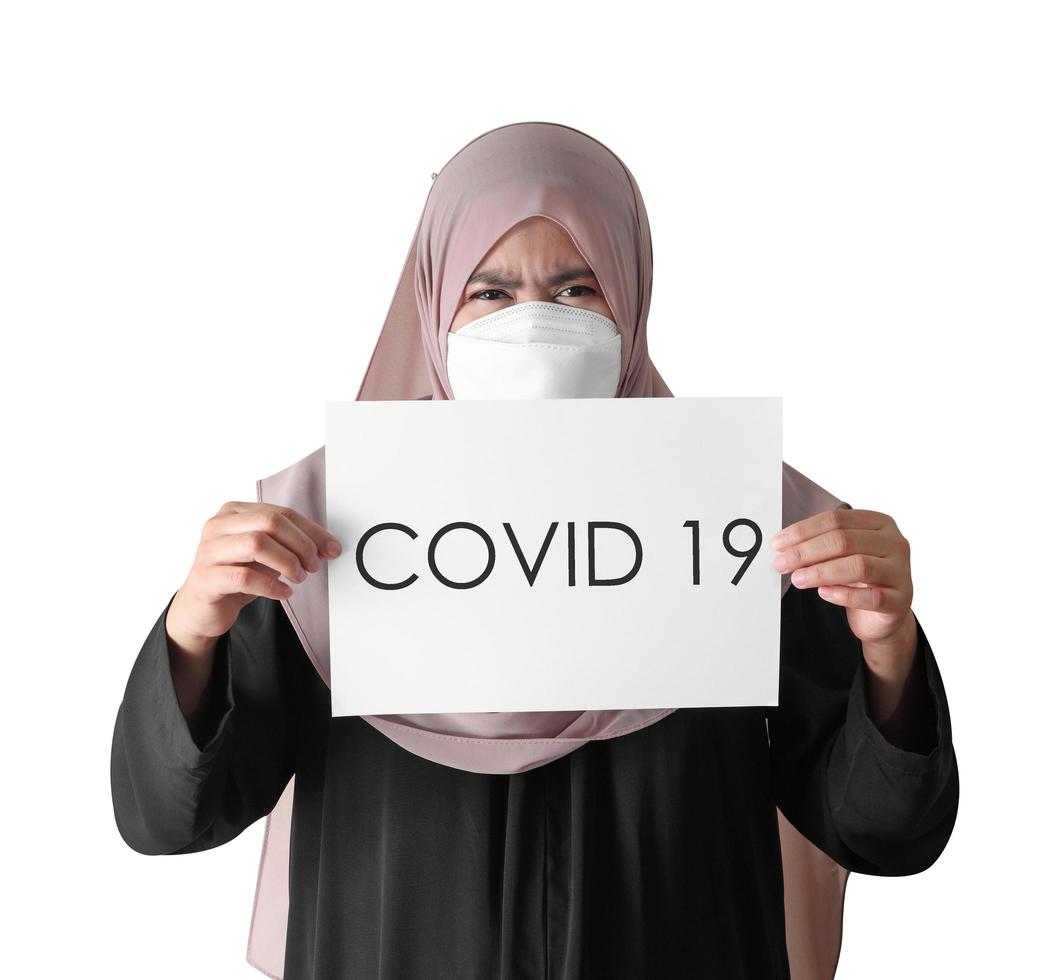 donna musulmana che indossa maschera chirurgica tenendo la carta su sfondo bianco foto