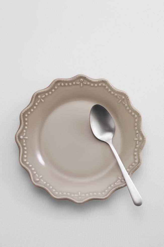 cucchiaio in un piatto di ceramica su sfondo pastello foto