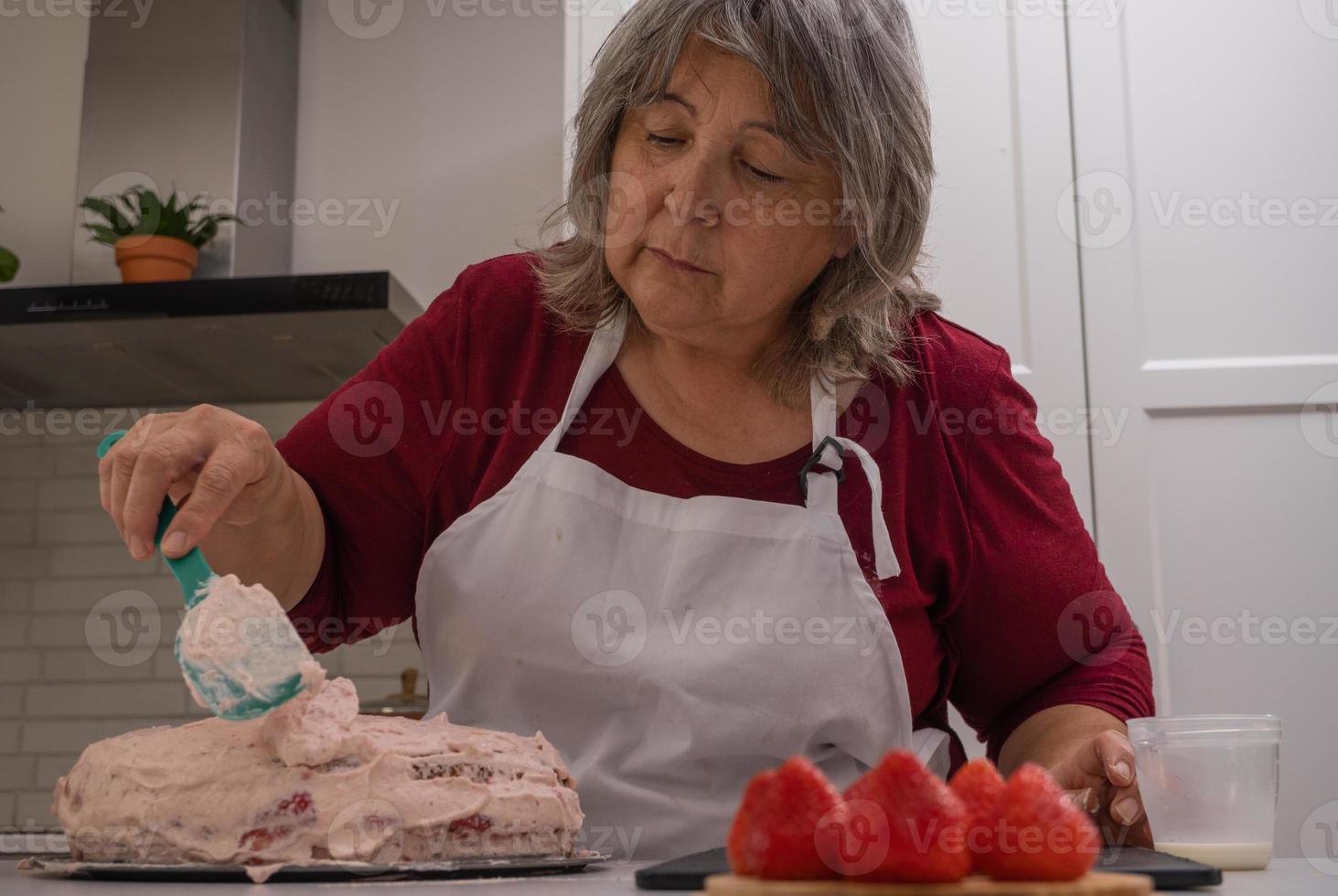 donna più anziana che fa una torta foto