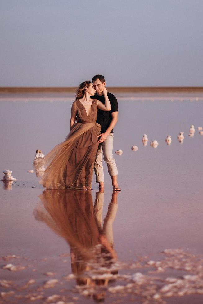 ragazza e un ragazzo sulla riva di un lago salato rosa foto