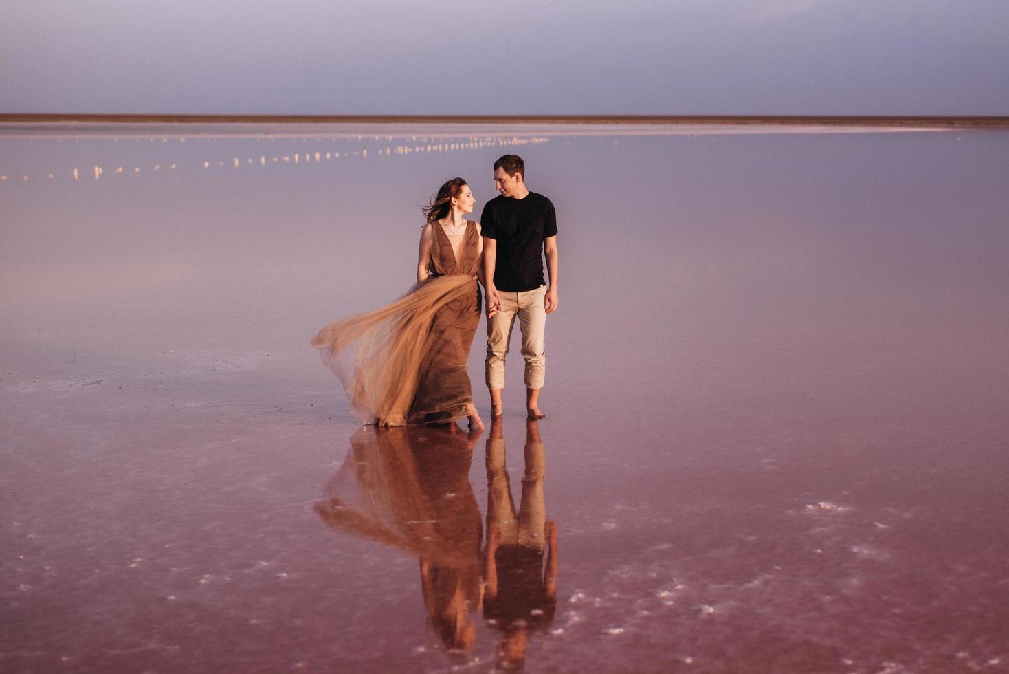 ragazza e un ragazzo sulla riva di un lago salato rosa foto