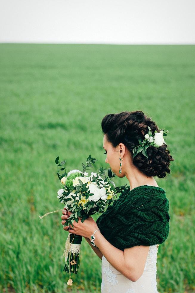 sposa con bouquet in abito avorio e scialle di maglia foto