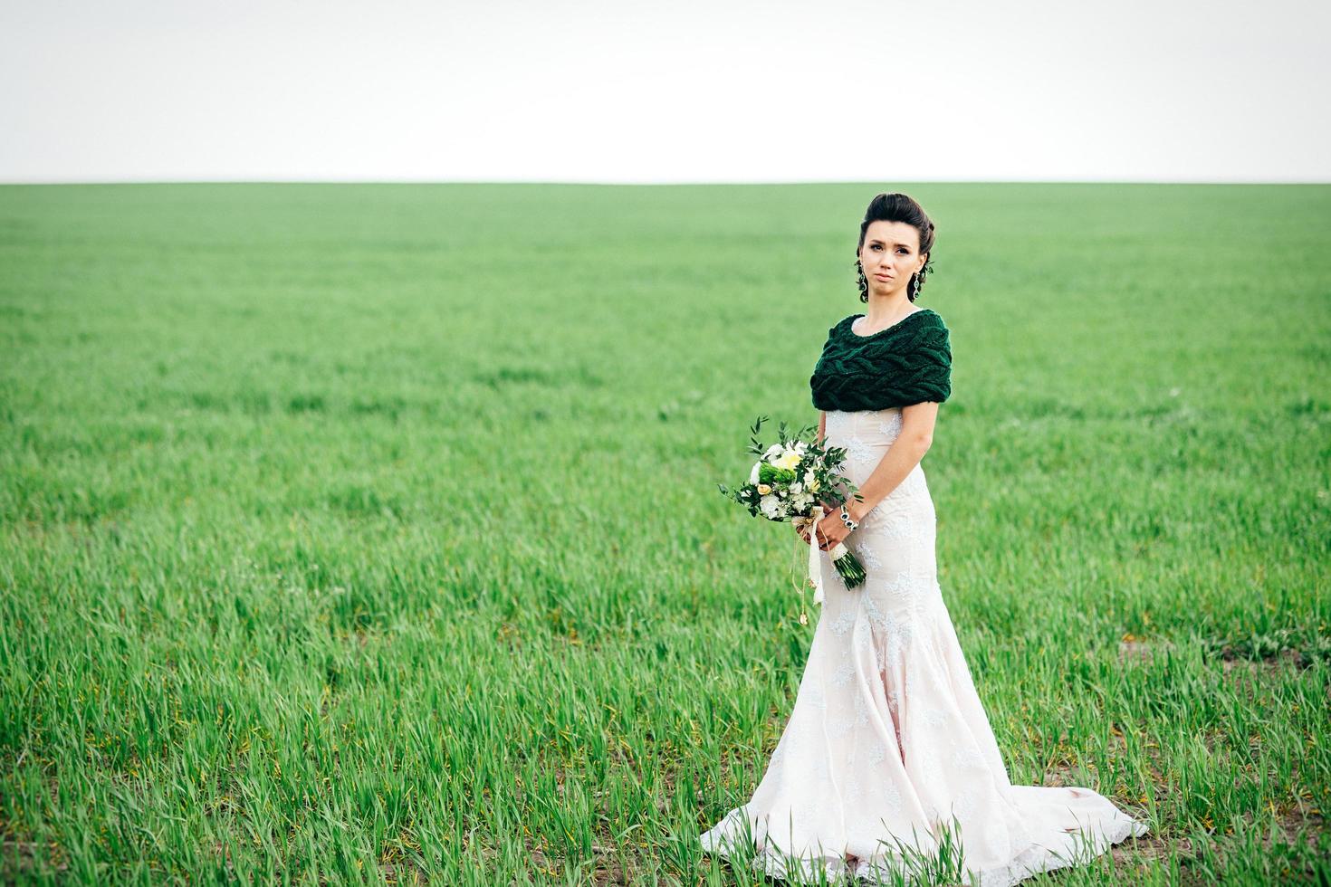 sposa con bouquet in abito avorio e scialle di maglia foto