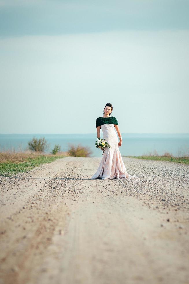 sposa con un mazzo di fiori in un abito avorio e uno scialle di maglia foto