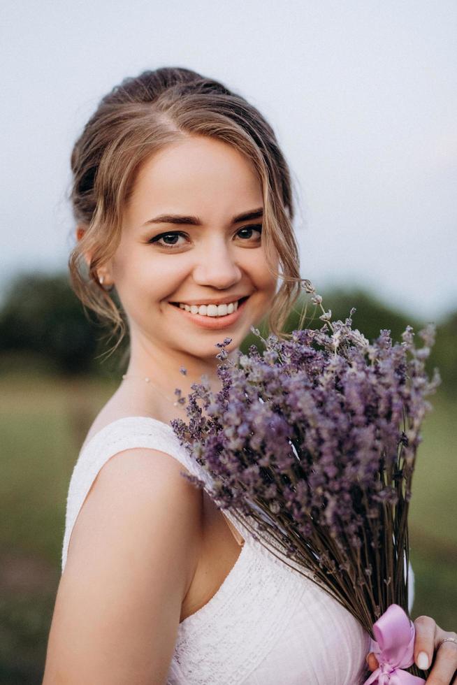 ragazza con un prendisole bianco e un ragazzo con una camicia bianca durante una passeggiata al tramonto con un bouquet foto