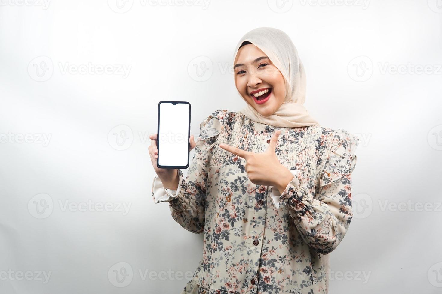 bella giovane donna musulmana asiatica scioccata, sorpresa, espressione wow, mano che tiene smartphone con schermo bianco o vuoto, promozione dell'app, promozione del prodotto, presentazione di qualcosa, isolato foto