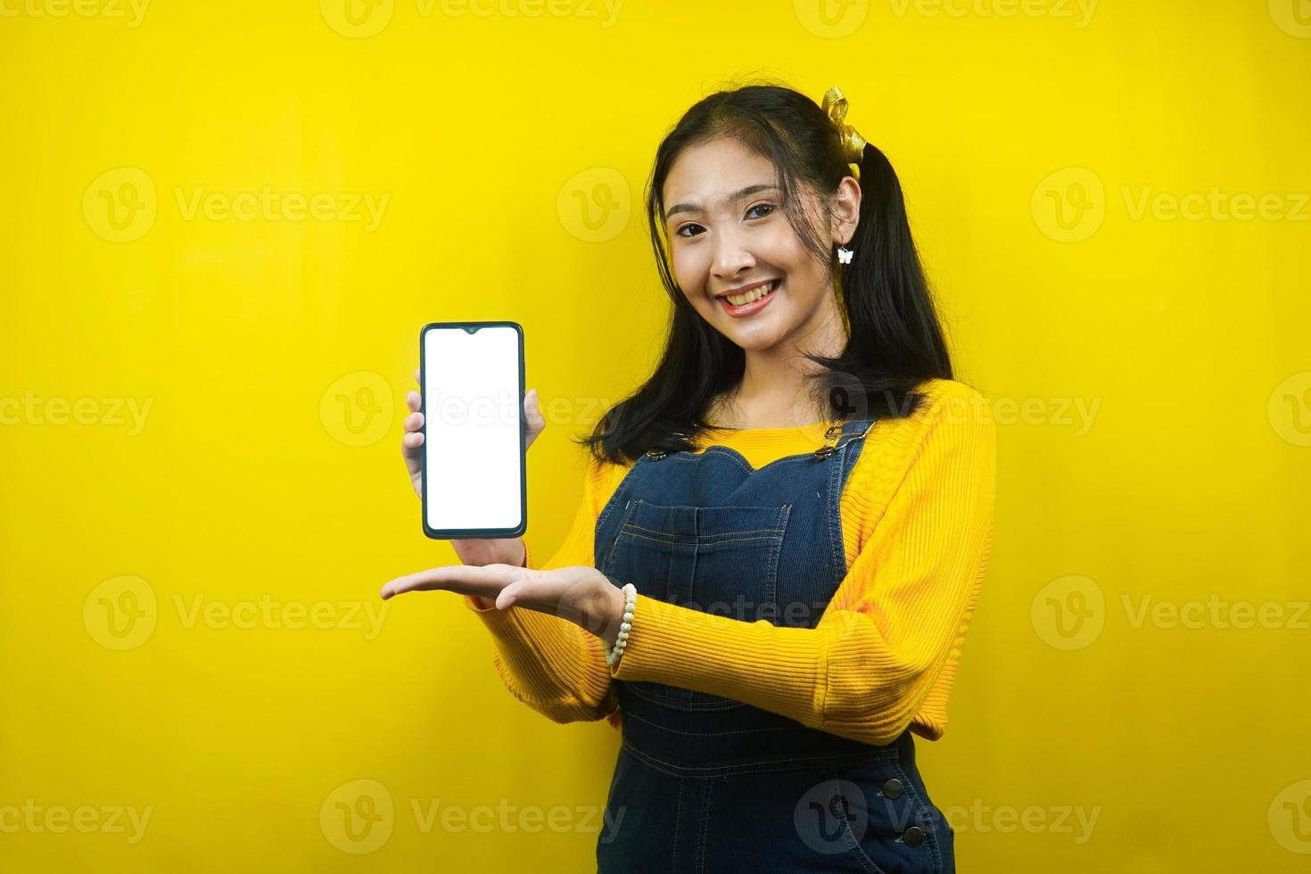 bella e carina giovane donna allegra, sicura di sé, con le mani in mano, smartphone con schermo bianco o bianco, promozione di app, promozione di prodotti, pubblicità, isolata foto