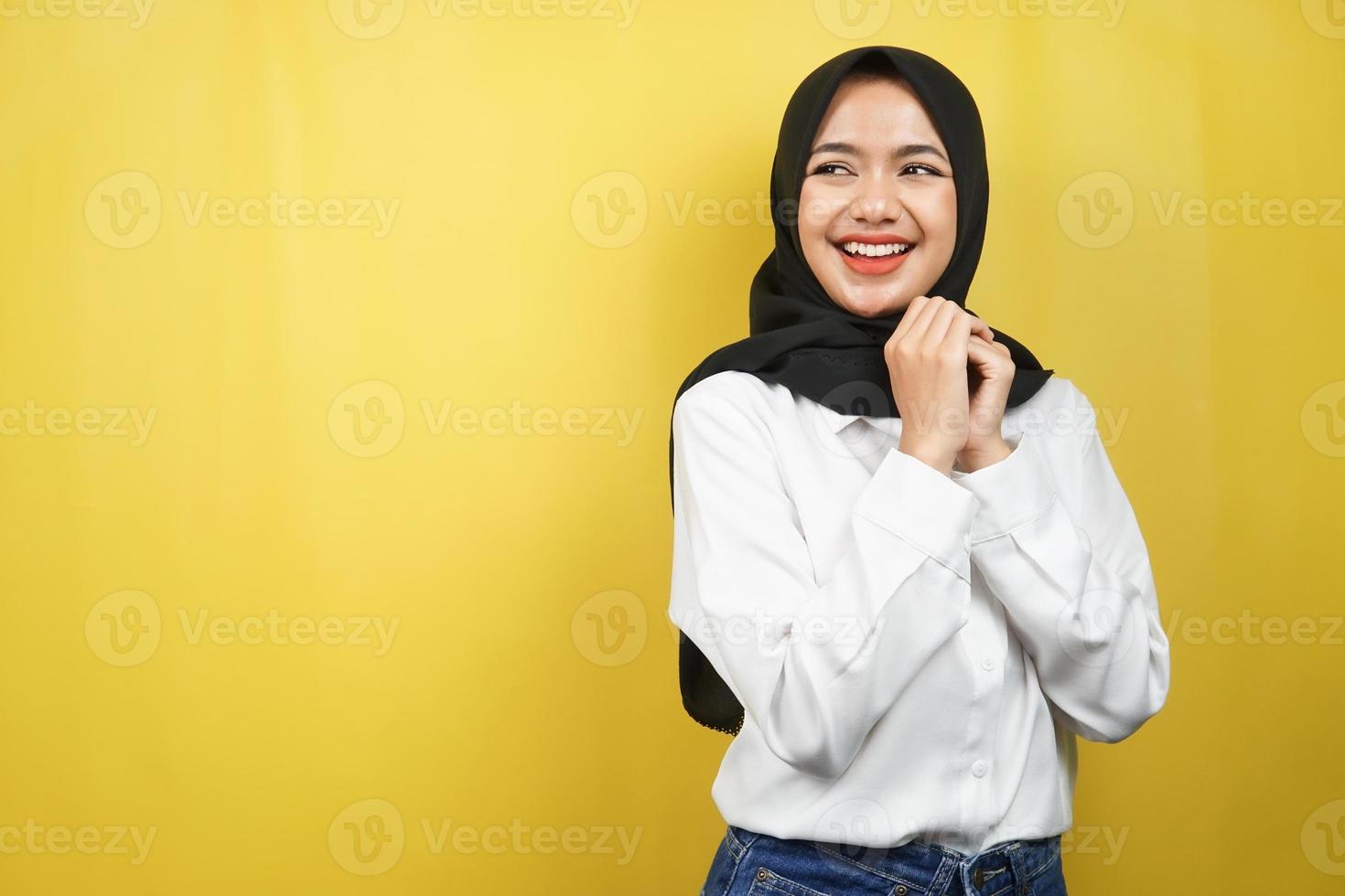 bella giovane donna musulmana asiatica sicura e allegra che sembra uno spazio vuoto che presenta qualcosa, isolato su sfondo giallo foto