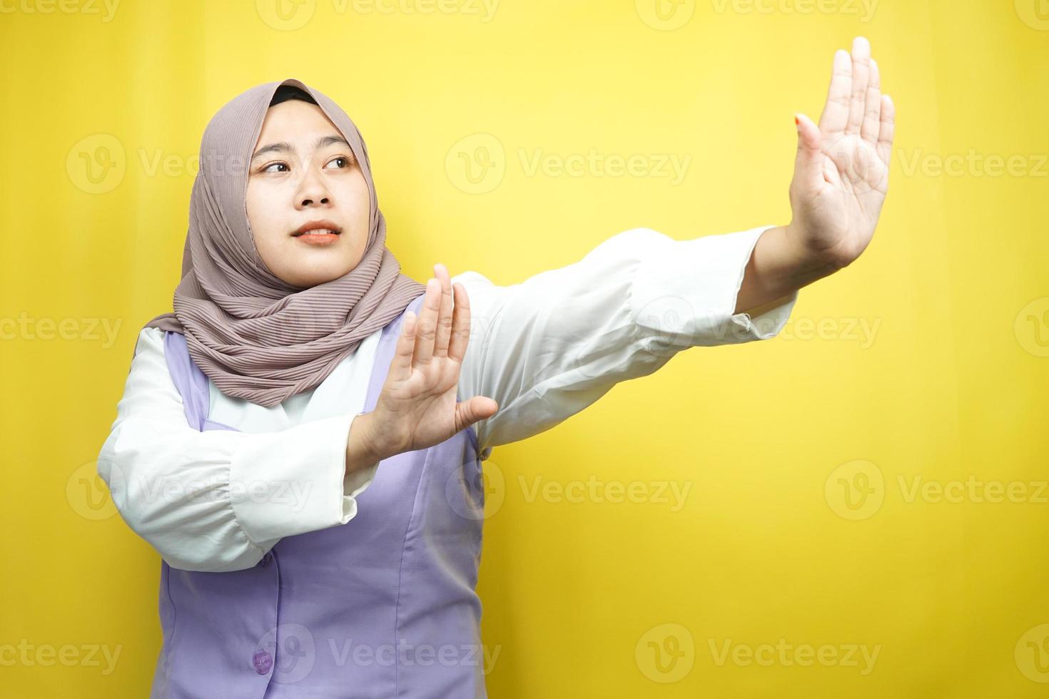 bella giovane donna musulmana asiatica con la mano che rifiuta qualcosa, mano che ferma qualcosa, antipatia per qualcosa nello spazio vuoto, isolato su sfondo giallo foto