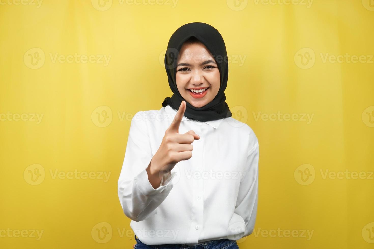 bella giovane donna musulmana asiatica sorridente sicura e allegra, con le mani che puntano alla telecamera, che puntano al pubblico, che puntano al cliente, isolato su sfondo giallo foto