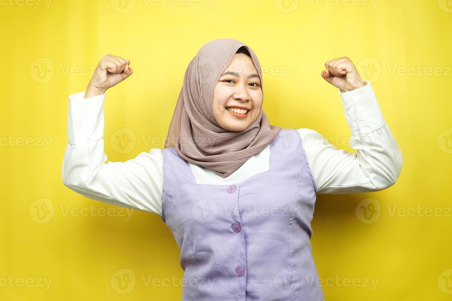 bella giovane donna musulmana asiatica con muscoli sollevati, braccia con segno di forza, isolata su sfondo giallo foto