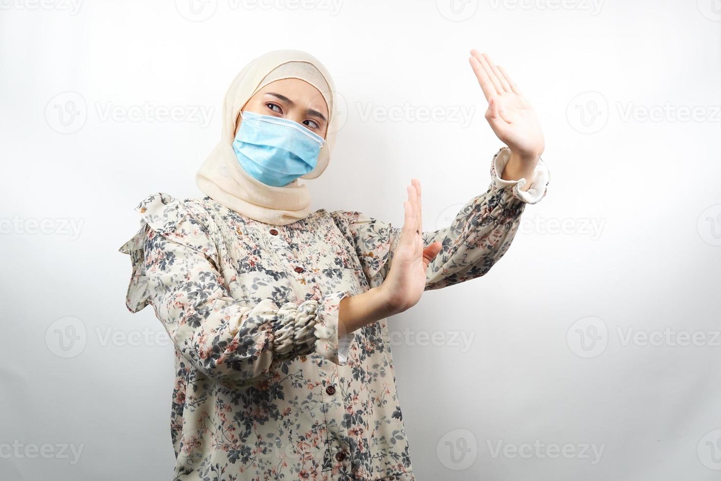 donna musulmana che indossa maschera medica con la mano che rifiuta qualcosa, mano che ferma qualcosa, mano che non gradisce qualcosa, isolato su sfondo bianco foto