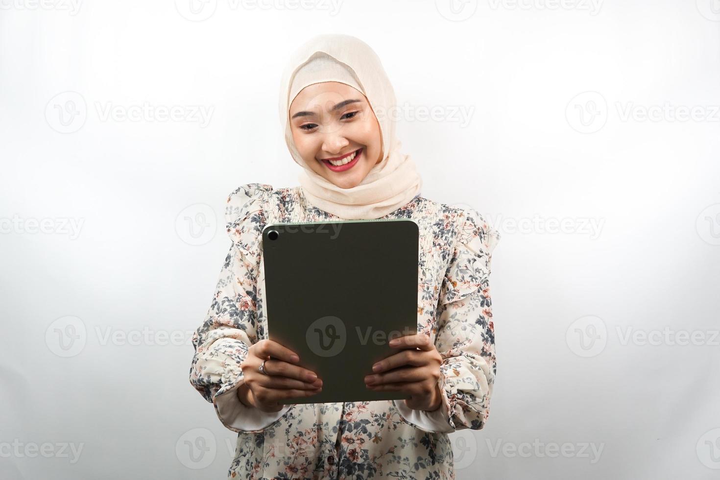 bella giovane donna musulmana asiatica sorridente, eccitata e allegra che tiene compressa, isolata su sfondo bianco foto