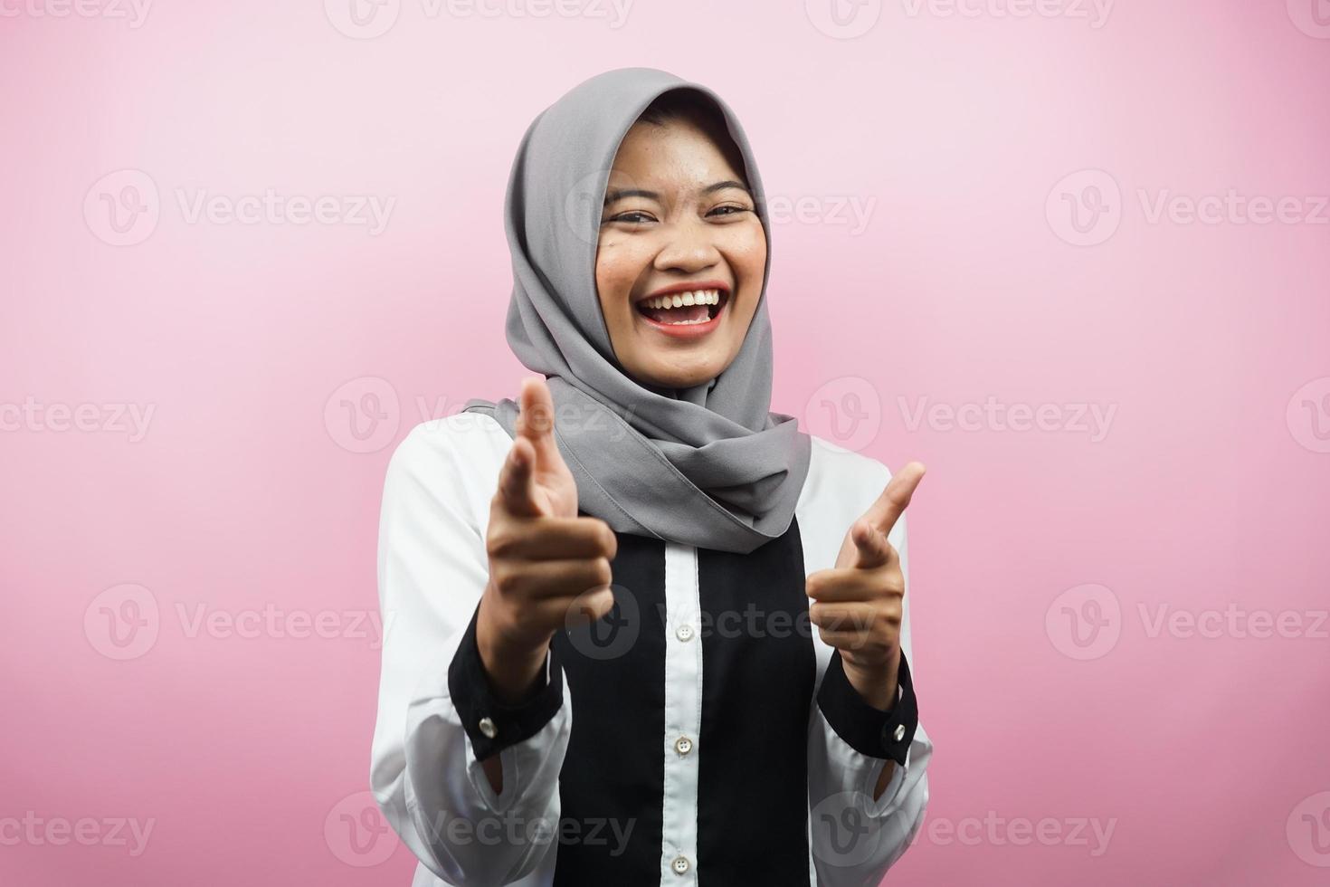 bella giovane donna musulmana asiatica sorridente sicura di sé, entusiasta e allegra con le mani che puntano alla telecamera, le mani che puntano al pubblico, di fronte alla telecamera isolata su sfondo rosa foto