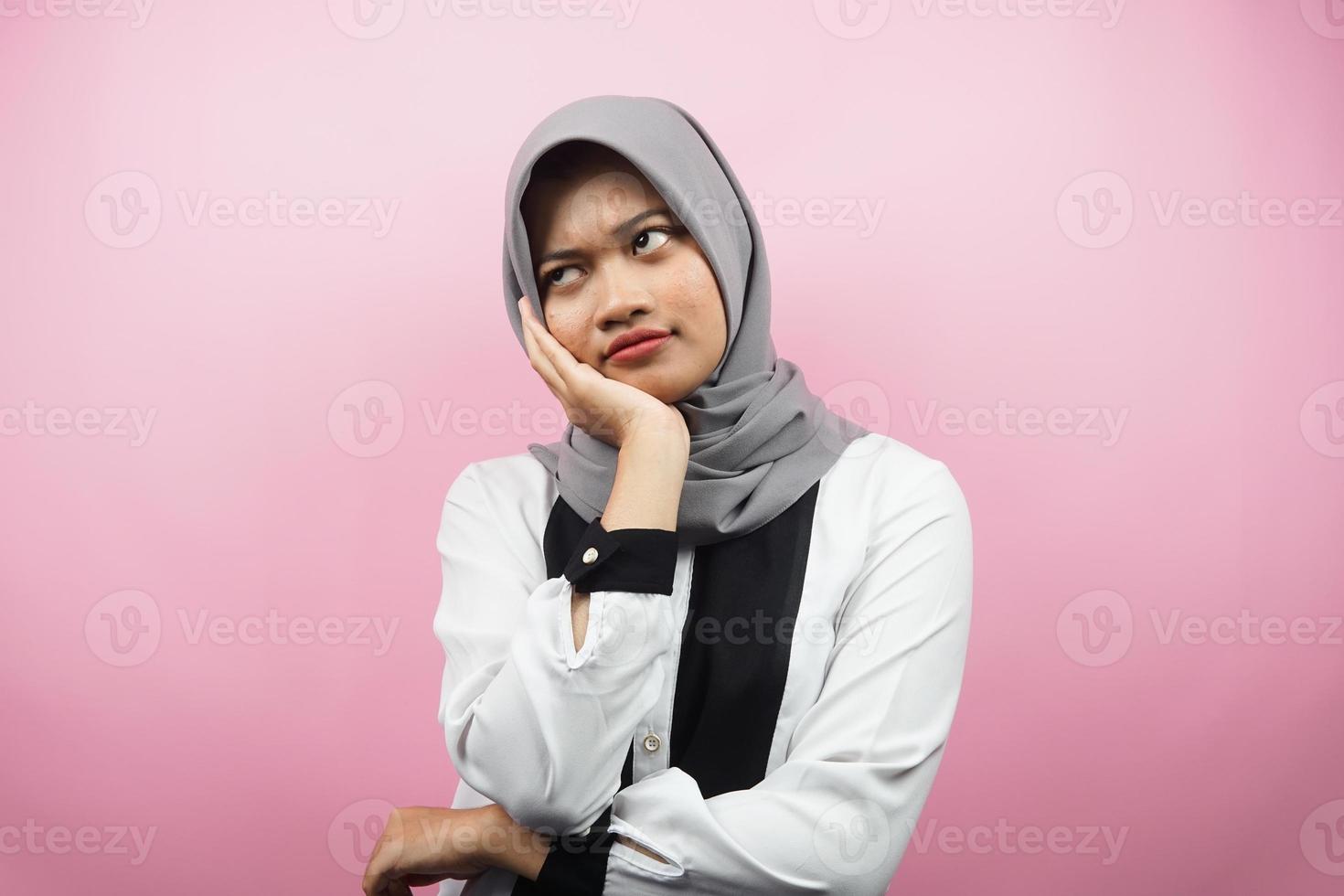 bella giovane donna musulmana asiatica che pensa, cerca idee, cerca soluzioni ai problemi, con le mani che tengono le guance, isolate su sfondo rosa foto