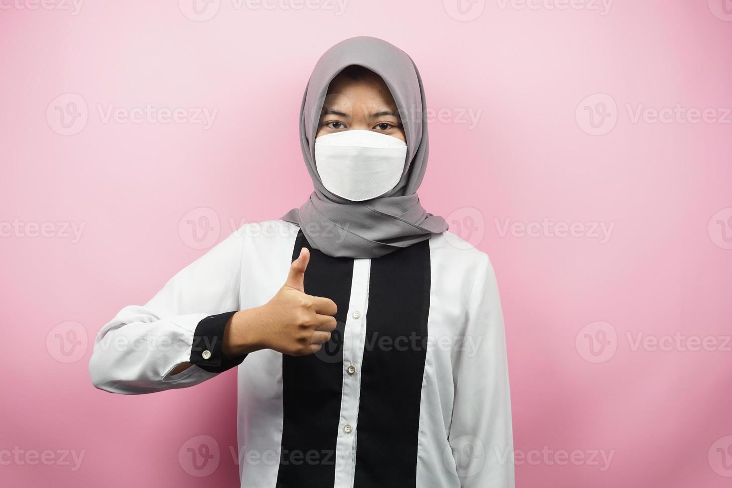 donna musulmana che indossa maschere bianche, movimento anti corona virus, movimento anti covid-19, movimento sanitario usando maschere, con le mani che mostrano segno ok, buon lavoro, successo, vittoria, isolato su sfondo rosa foto