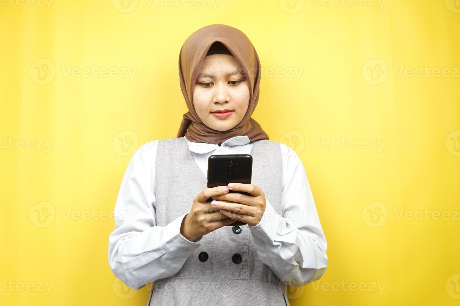 bella asiatica giovane donna musulmana che tiene smartphone isolato su sfondo giallo foto