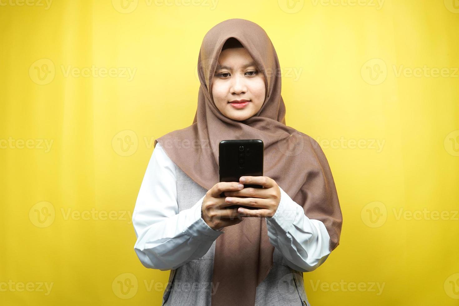 bella asiatica giovane donna musulmana che tiene smartphone isolato su sfondo giallo foto