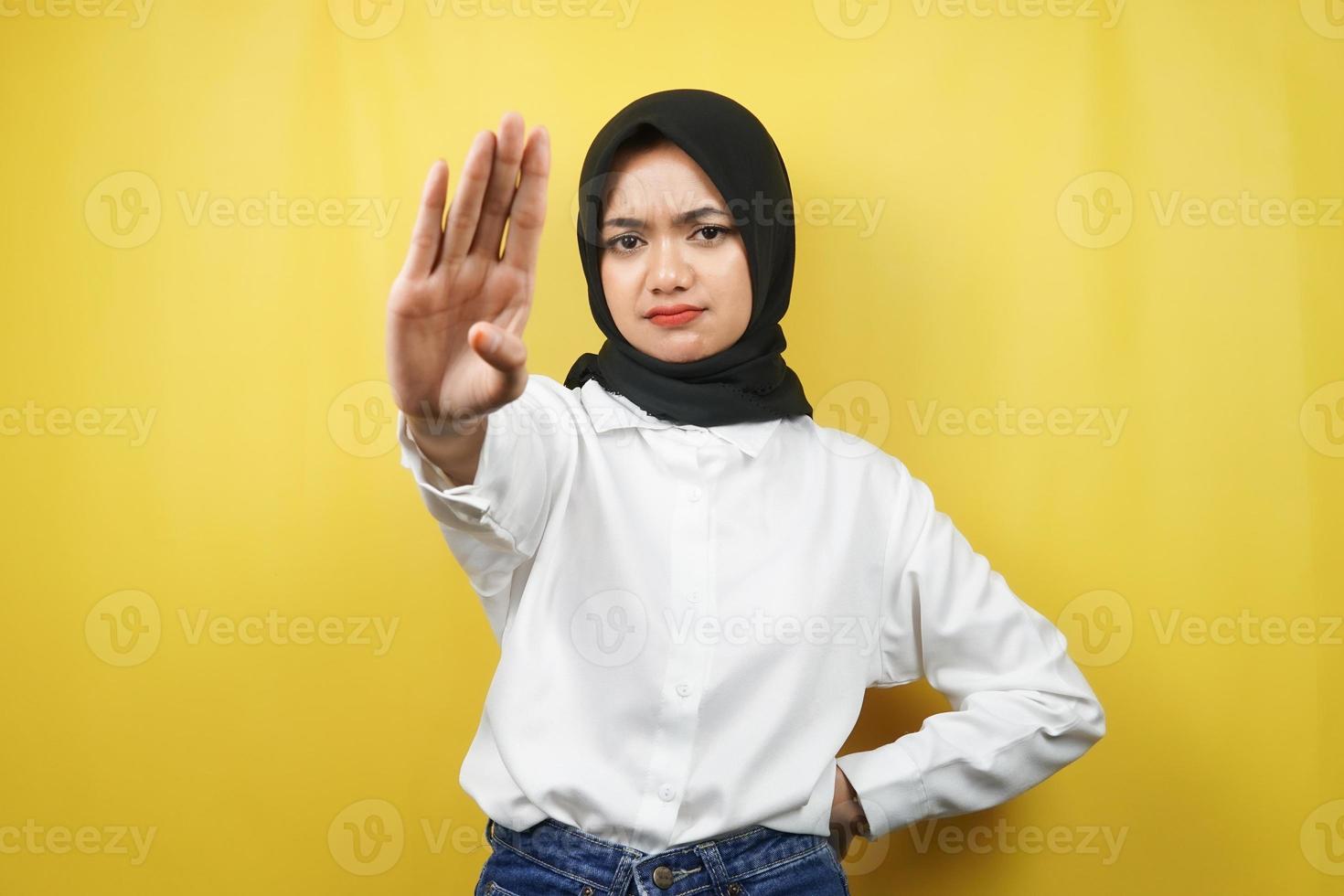 bella giovane donna musulmana asiatica con la mano del segnale di stop, rifiutare la mano del segno, mano del segnale di divieto, non avvicinarsi alla mano, stare lontano dalla mano del segno, non muovere la mano del segno, isolata su sfondo giallo foto