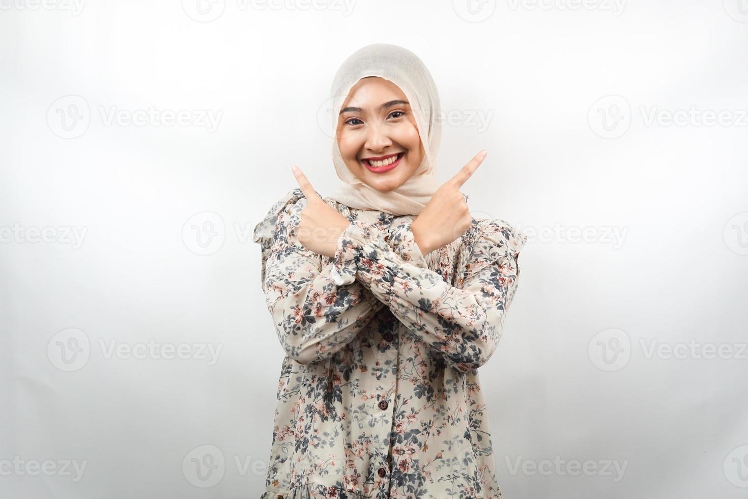 bella giovane donna musulmana asiatica sorridente sicura di sé, entusiasta, allegra con le mani che puntano lo spazio vuoto presentando qualcosa, guardando la telecamera isolata su sfondo bianco, concetto pubblicitario foto