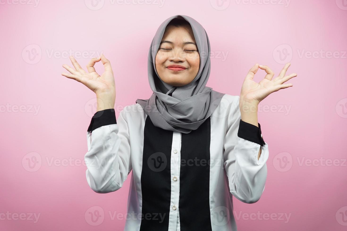 bella giovane donna musulmana con le mani che meditano segno, sorridente comodo e felice, isolato su sfondo rosa foto