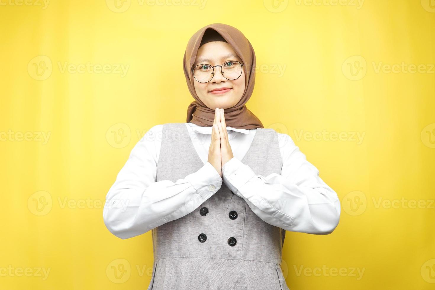 bella giovane donna musulmana asiatica con le mani sul viso, scusandosi, sentendosi in colpa, eid ul fitr e eid ul adha, sorridente fiduciosa, entusiasta e allegra, di fronte alla telecamera isolata foto