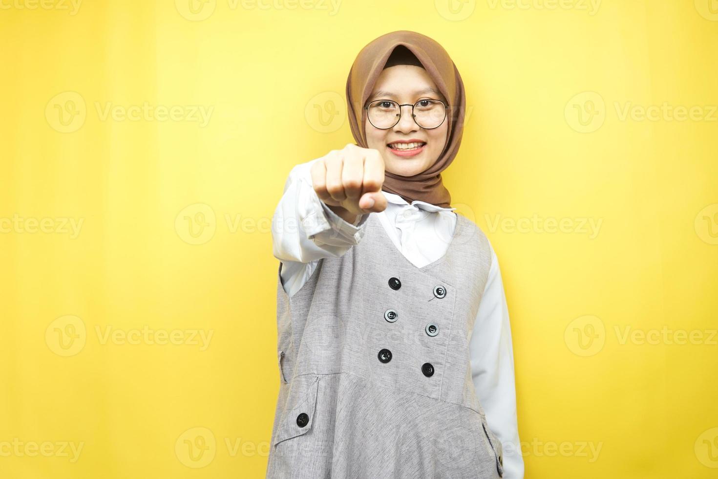 bella giovane donna musulmana asiatica sorridente sicura di sé, entusiasta e allegra con i pugni serrati alla telecamera, pugni, combattimenti, cooperazione, occhi luccicanti, guardando la telecamera isolata foto