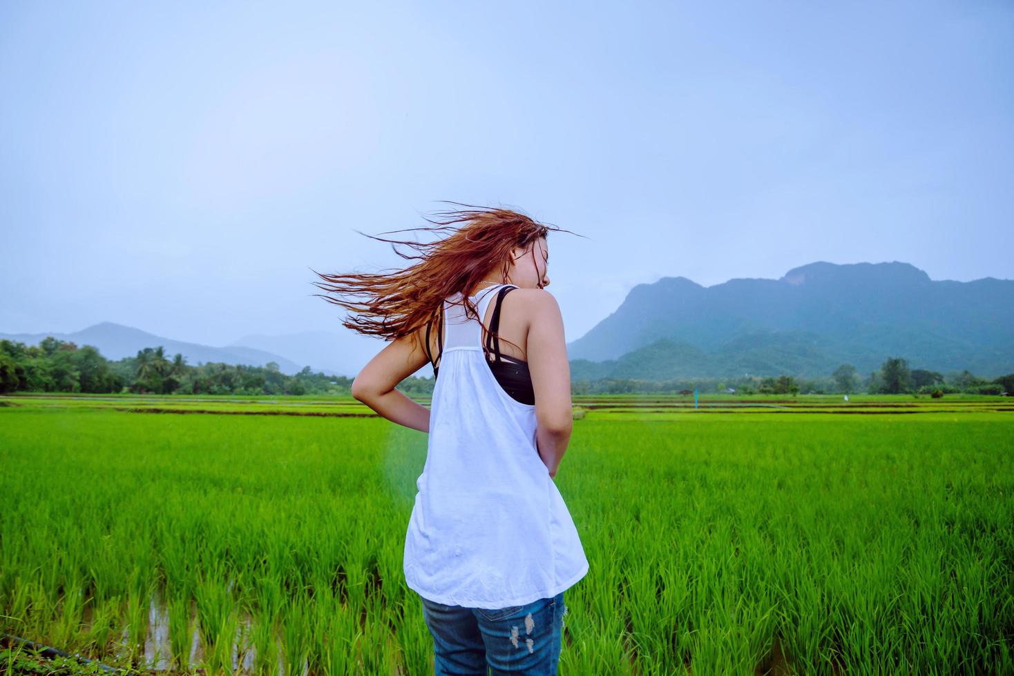 le donne asiatiche viaggiano rilassandosi durante le vacanze. La ragazza sorrise felice e si godette la pioggia che cadeva. viaggiare in campagna, risaie verdi, viaggiare in thailandia. foto