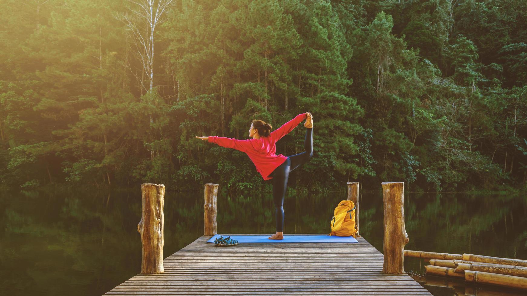 le donne asiatiche si rilassano durante le vacanze. gioca se lo yoga. sulla montagna, esercitarsi, giocare se yoga sul ponte di bambù accanto al lago nella nebbia a pang ung, thailandia. foto