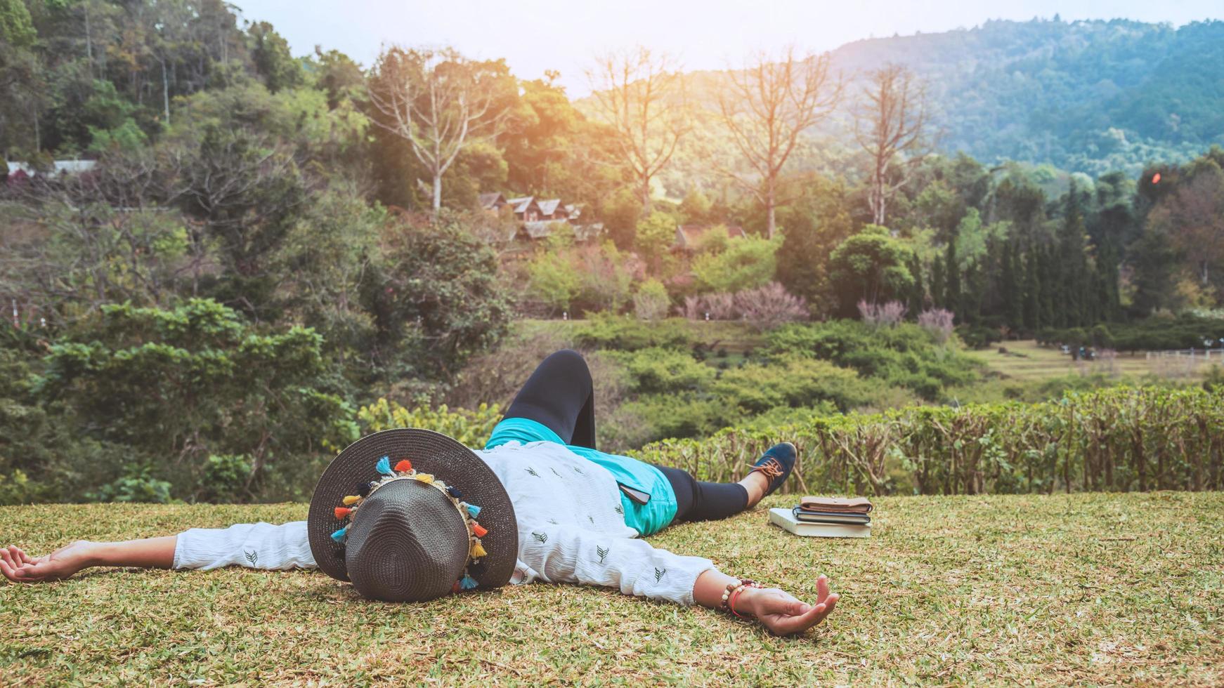 natura di viaggio donna asiatica. viaggiare rilassati. dormire sul prato del parco. in estate. foto