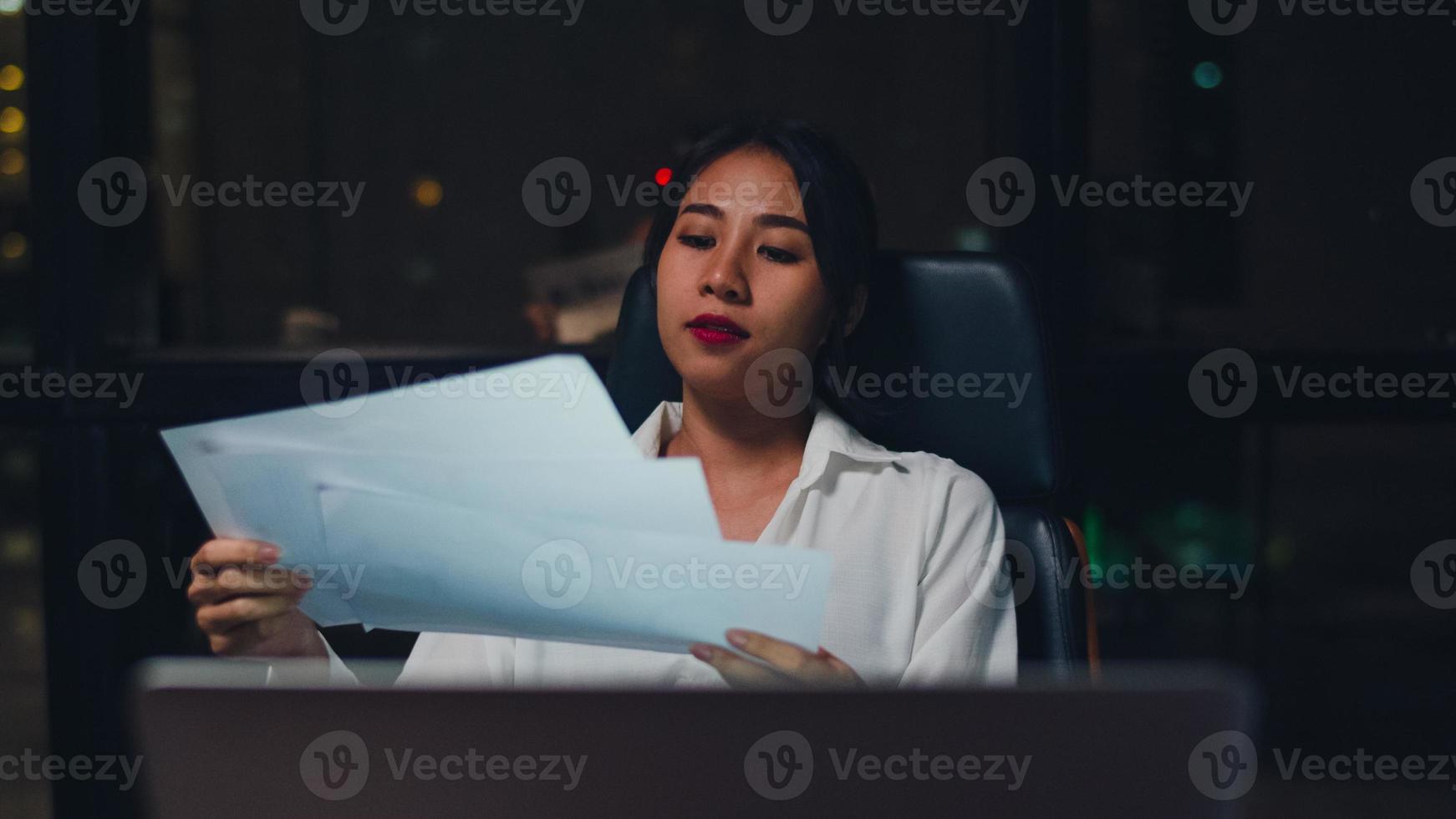giovane imprenditrice cinese millenaria che lavora a tarda notte stressata con problemi di ricerca del progetto sul laptop nella sala riunioni in un piccolo ufficio moderno. concetto di sindrome di burnout professionale di persone asiatiche. foto