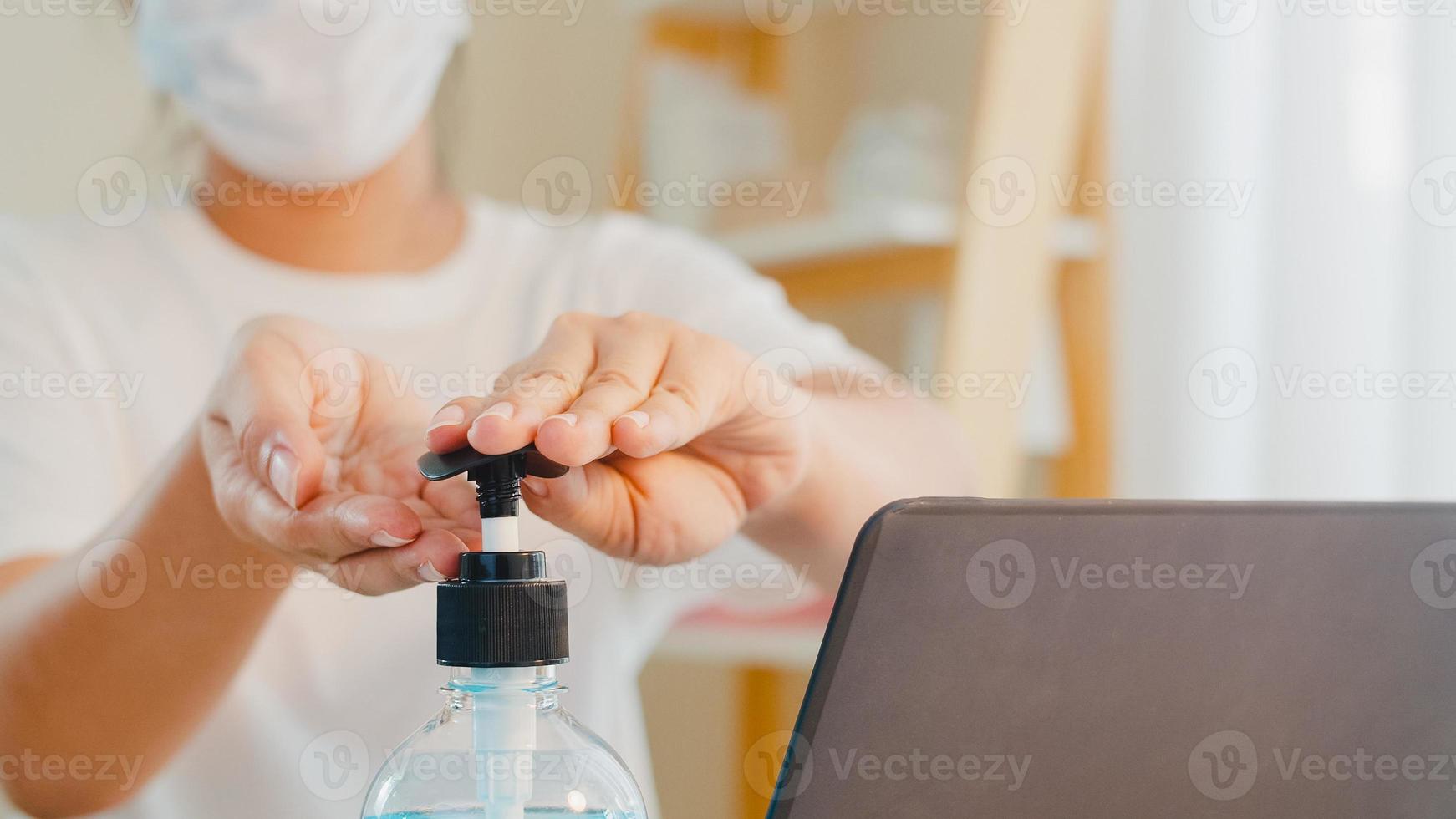 donna asiatica che usa un disinfettante per le mani in gel alcolico lavarsi le mani prima di aprire il laptop per proteggere il coronavirus. le donne spingono l'alcol a pulire per l'igiene quando il distanziamento sociale resta a casa e il tempo di autoquarantena foto