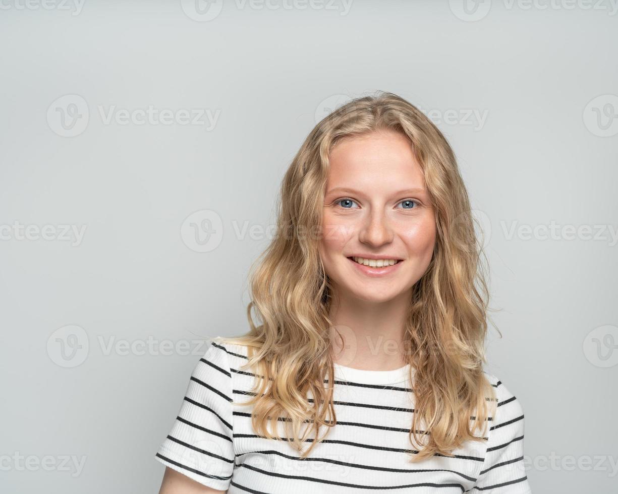 bella giovane donna bionda sorridente senza trucco sul muro bianco. foto