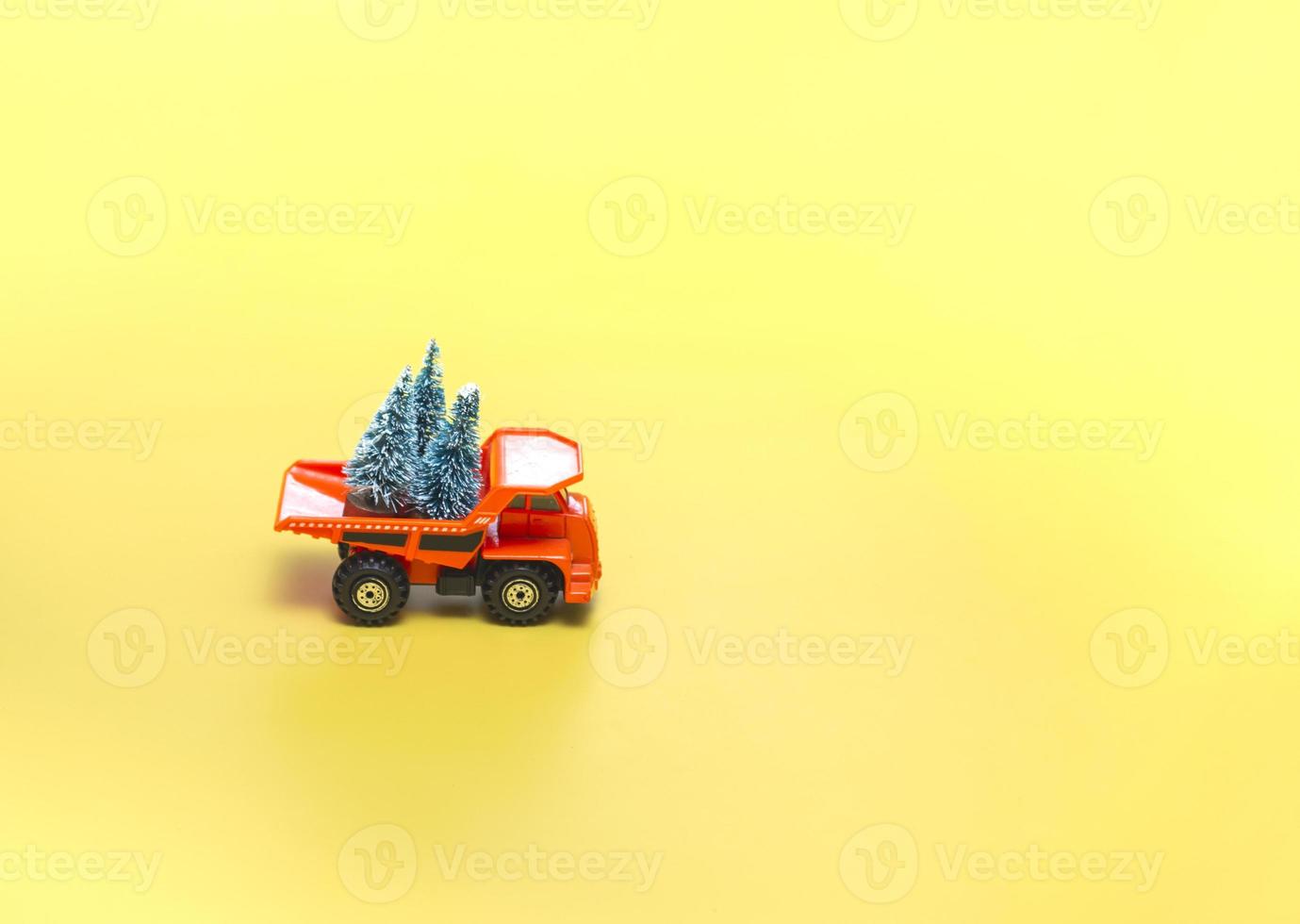 camion giallo con alberi di natale su fondo beige con luci. concetto di vacanze. da vicino, con copia spazio. foto