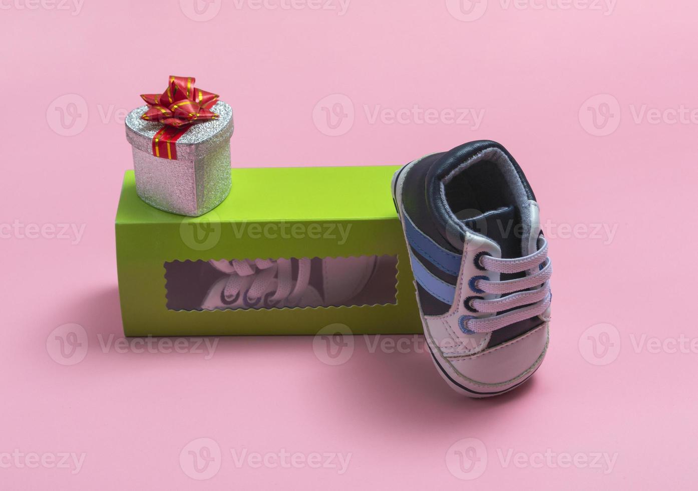 mockup di scarpe per bambini. Close up di una confezione regalo e gumshoes per un neonato su uno sfondo colorato. un regalo a papà foto