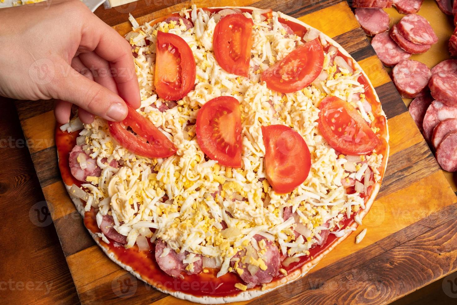 pizza in cottura con pomodorini e salsiccia foto