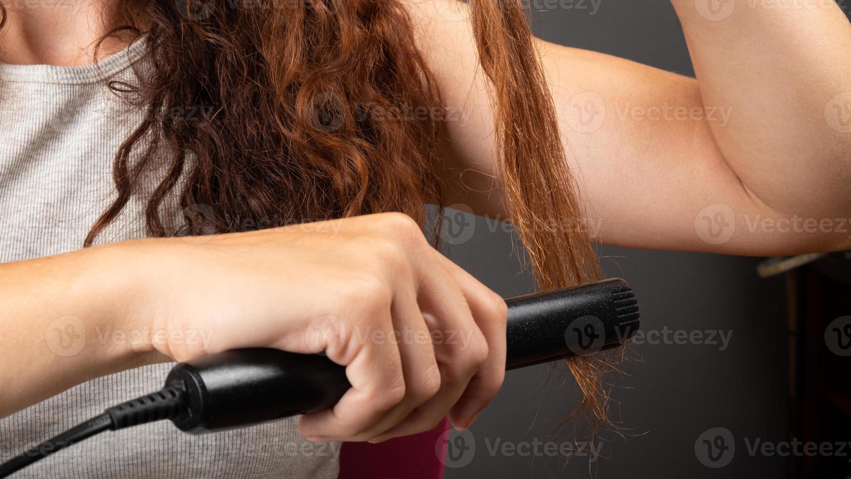 stiratura dei capelli con un ferro da stiro, cura dei capelli di bellezza foto