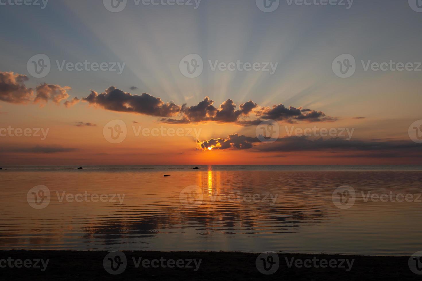 sole tra le nuvole durante l'alba sul mare foto