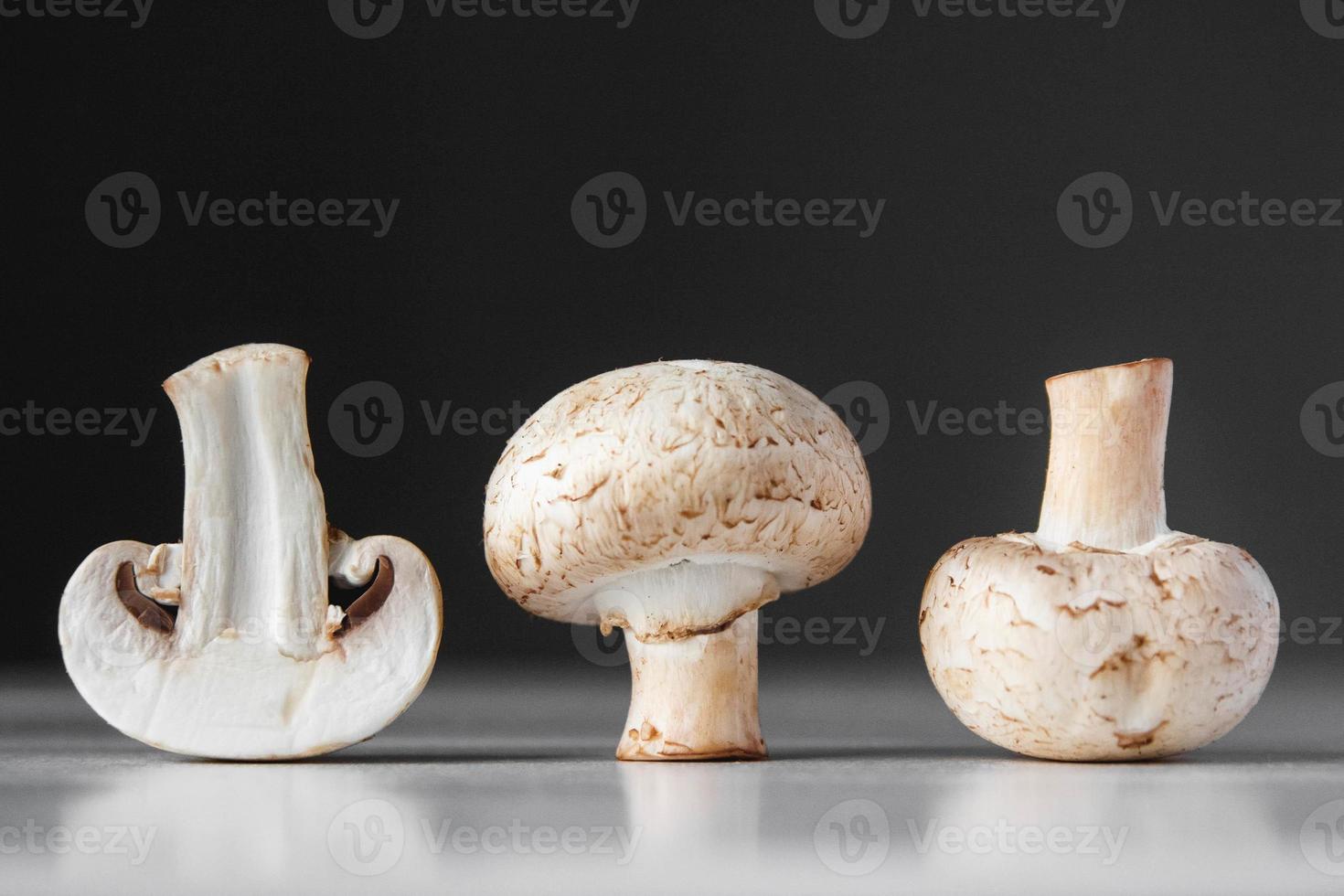funghi champignon giacciono in fila su un tavolo bianco su sfondo scuro foto