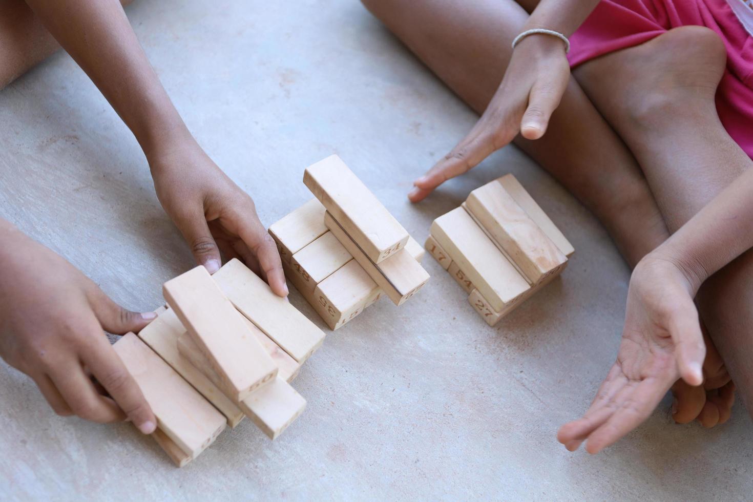 bambini che giocano con blocchi di legno sul pavimento di cemento foto