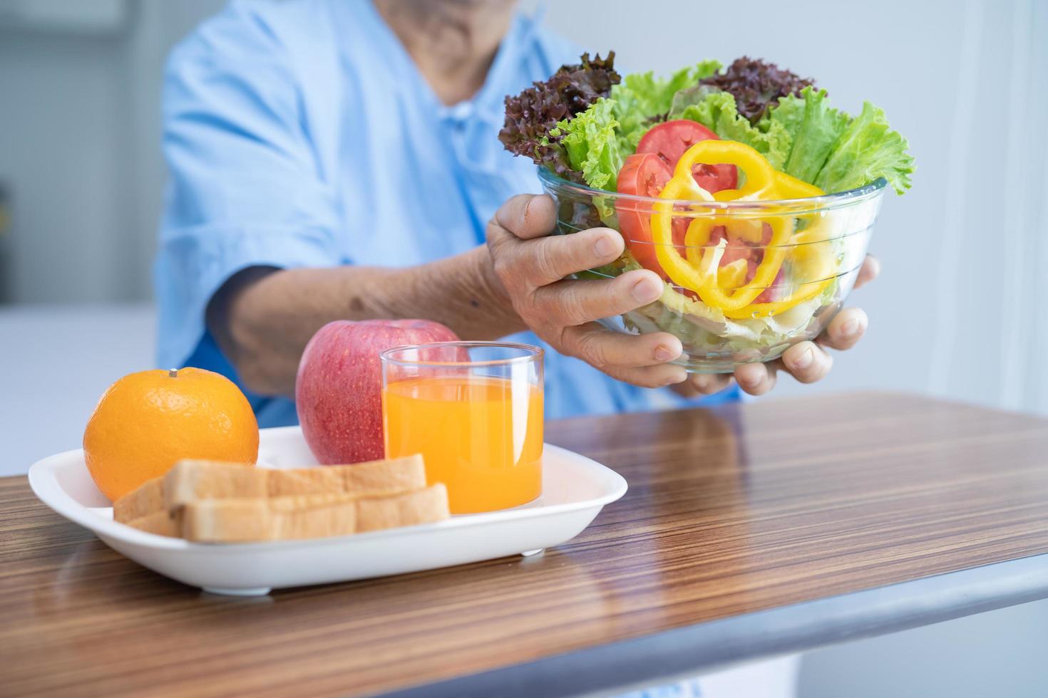 asiatico anziano o anziana signora anziana paziente che mangia colazione vegetale cibo sano con speranza e felice mentre è seduto e affamato sul letto in ospedale. foto
