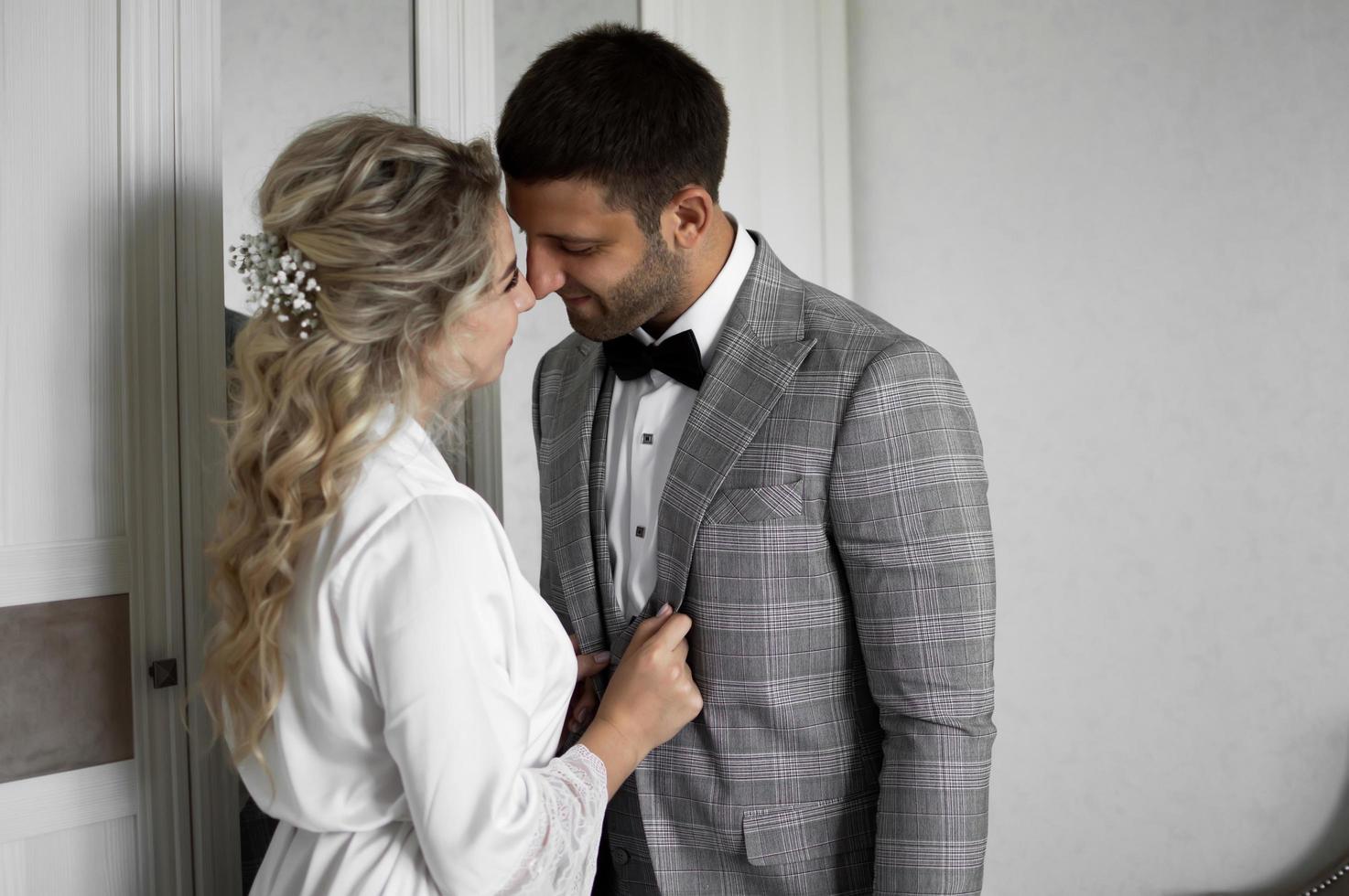 mattina degli sposi. la sposa aiuta a vestire lo sposo il giorno del matrimonio. messa a fuoco selettiva.grana della pellicola. foto