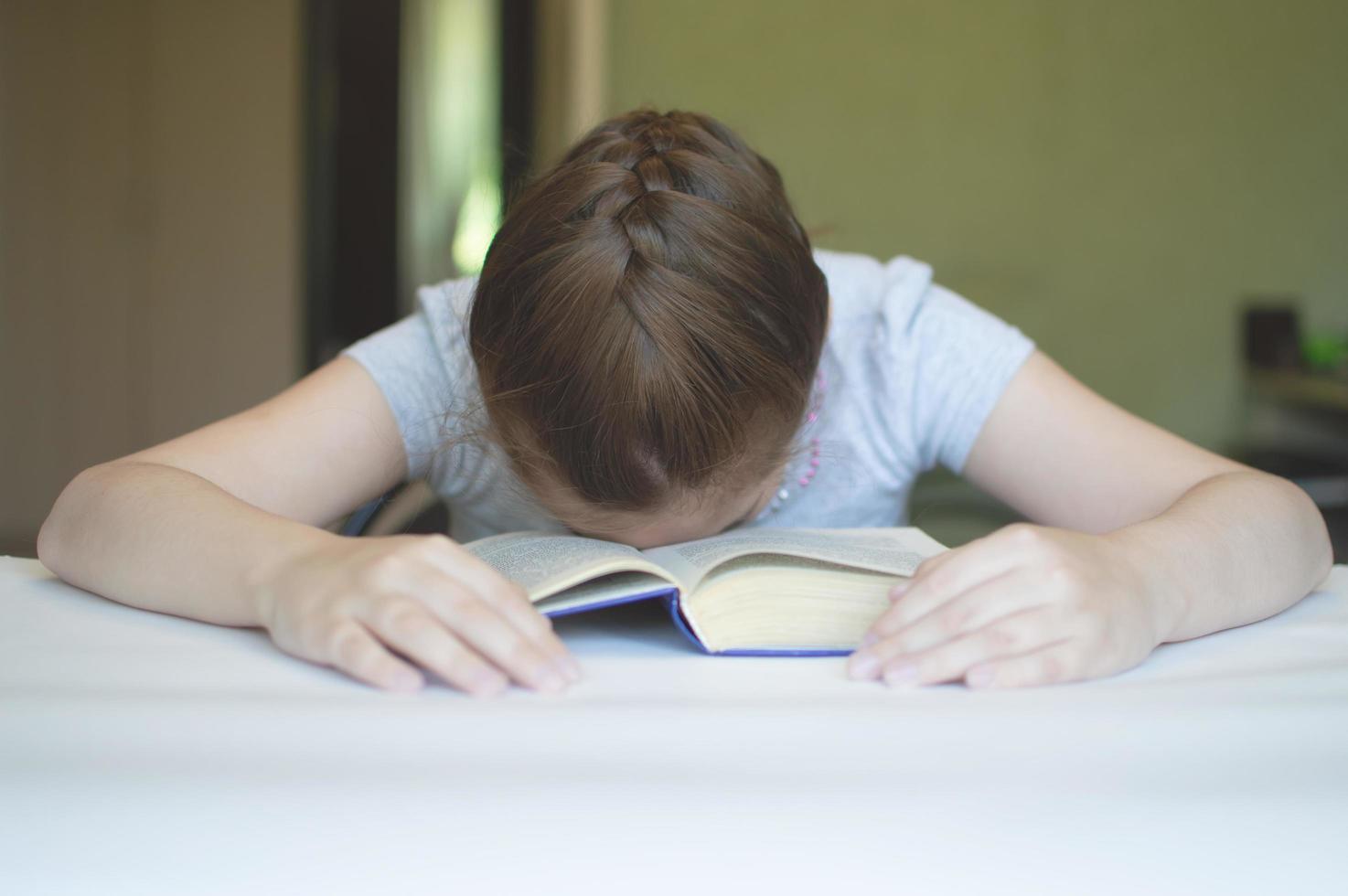 bambino che legge un libro a tavola foto