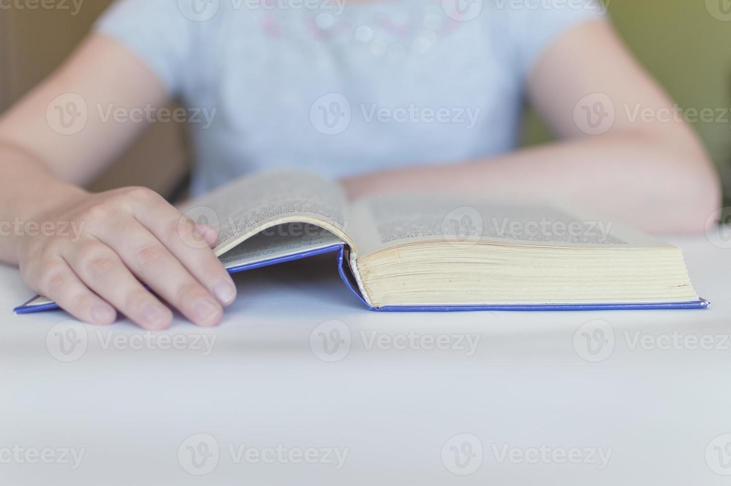 bambino che legge un libro a tavola foto
