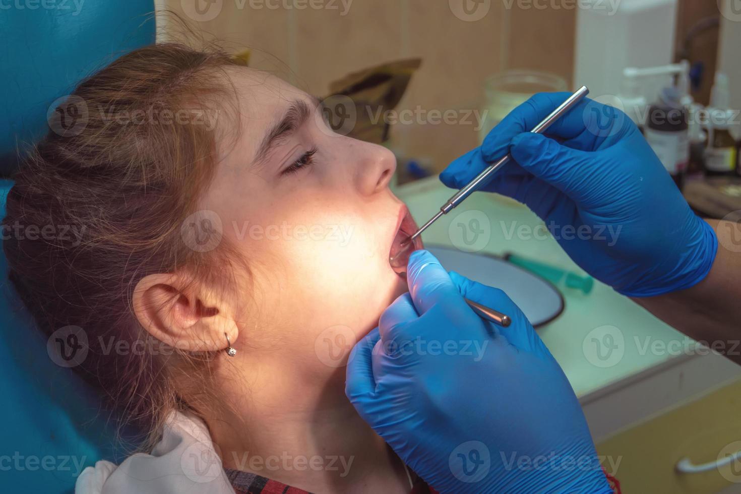 ragazza adolescente a un ricevimento in ufficio dal dentista seduto su una sedia. odontoiatria, dolore, paura foto