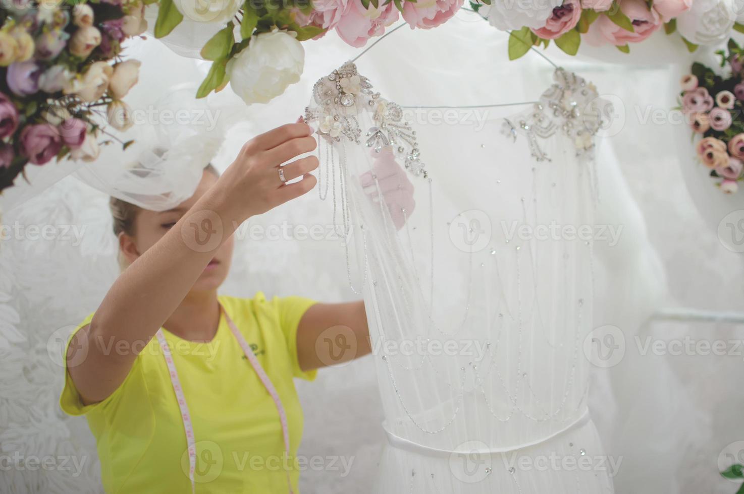 una sarta in un salone di nozze sta preparando un vestito per la vendita. abito da sposa arco da giardino foto