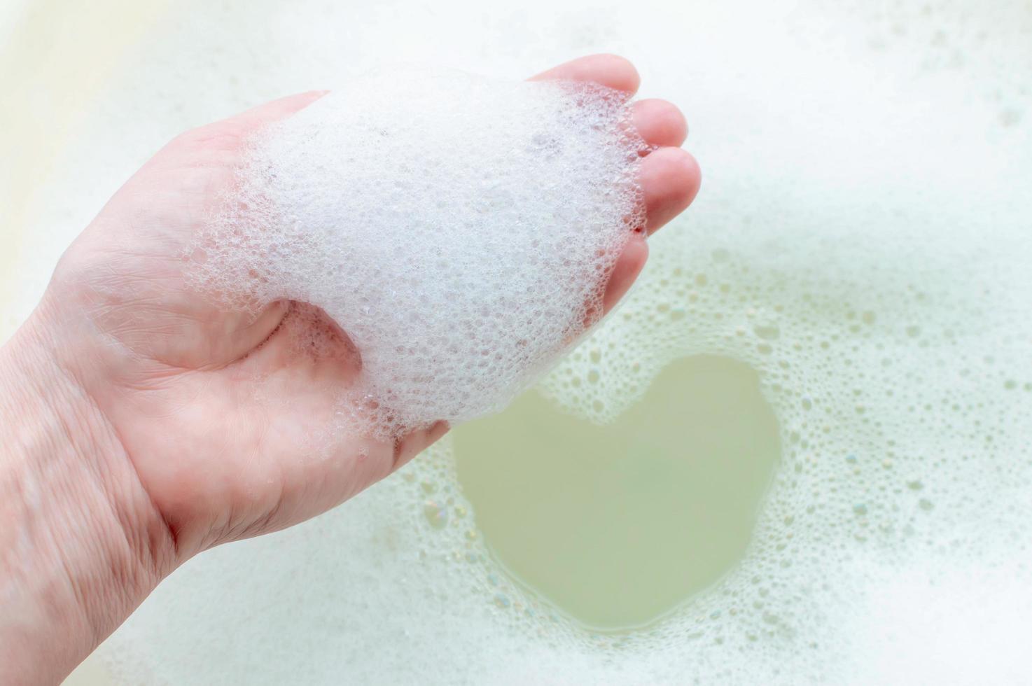 schiuma di sapone sulla mano di una persona su uno sfondo di schiuma di sapone. il concetto di pulizia e igiene. foto