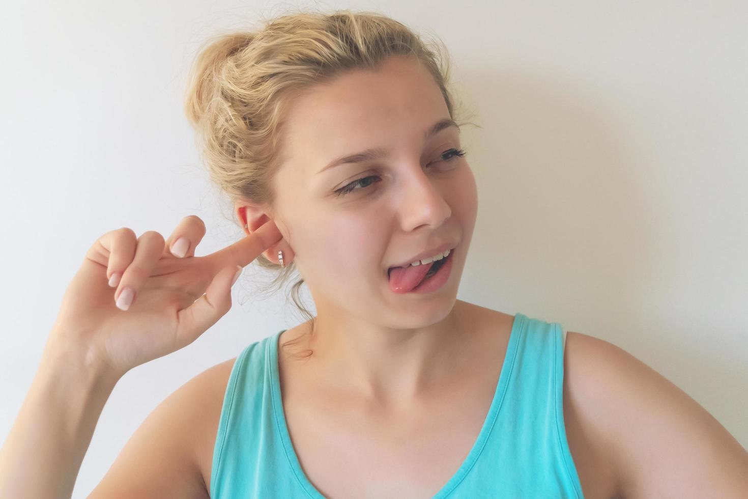 ragazza con i capelli biondi gioca le espressioni facciali, costruisce facce foto